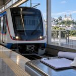 Trem moderno do Metrô Bahia em estação, com capacete e prancheta de trabalho