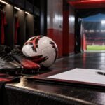 Bola, chuteiras e contrato em vestiário de futebol nas cores rubro-negras