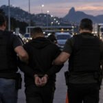 Policiais conduzem suspeito durante operação em rodovia no Rio de Janeiro