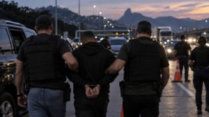 Policiais conduzem suspeito durante operação em rodovia no Rio de Janeiro