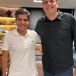 ACM Neto, de camisa polo branca, posa sorrindo ao lado de Reinaldinho Braga, de camisa preta, em ambiente interno