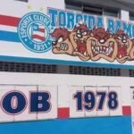 Fachada da sede social da Bamor, pintada em azul, vermelho e branco, com o escudo do Esporte Clube Bahia e o mascote da torcida