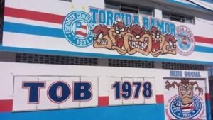 Fachada da sede social da Bamor, pintada em azul, vermelho e branco, com o escudo do Esporte Clube Bahia e o mascote da torcida