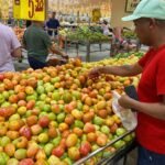 Consumidores escolhem tomates em supermercado durante pesquisa de preços