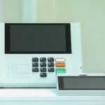 Urna eletrônica brasileira modelo UE2020 sobre bancada, com o terminal do mesário ao lado